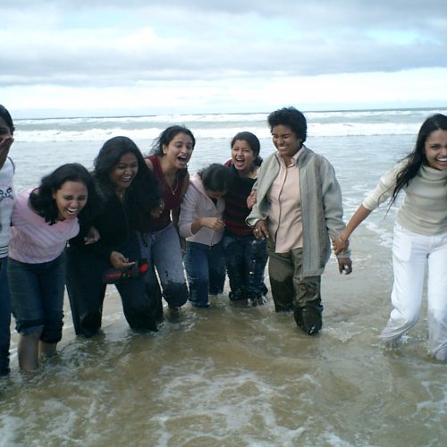 Team of female Indian Nurses standing together laughing in the water while their clothes get wet!