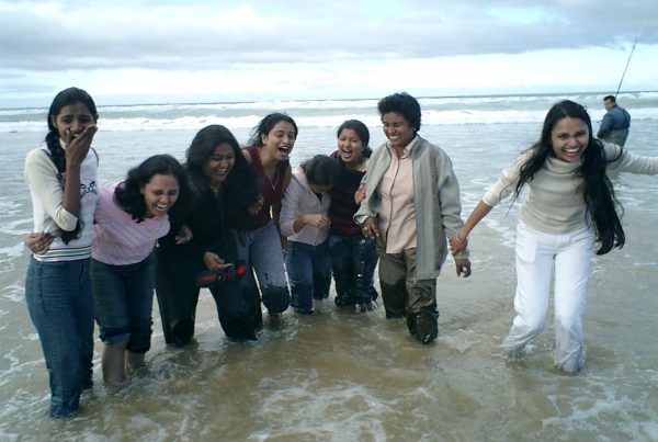 Team of female Indian Nurses standing together laughing in the water while their clothes get wet!